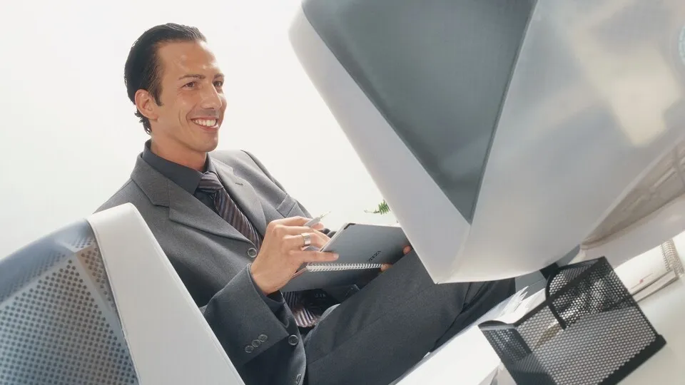 Manager sitzt sitzt mit Terminplaner an Schreibtisch vor Monitor